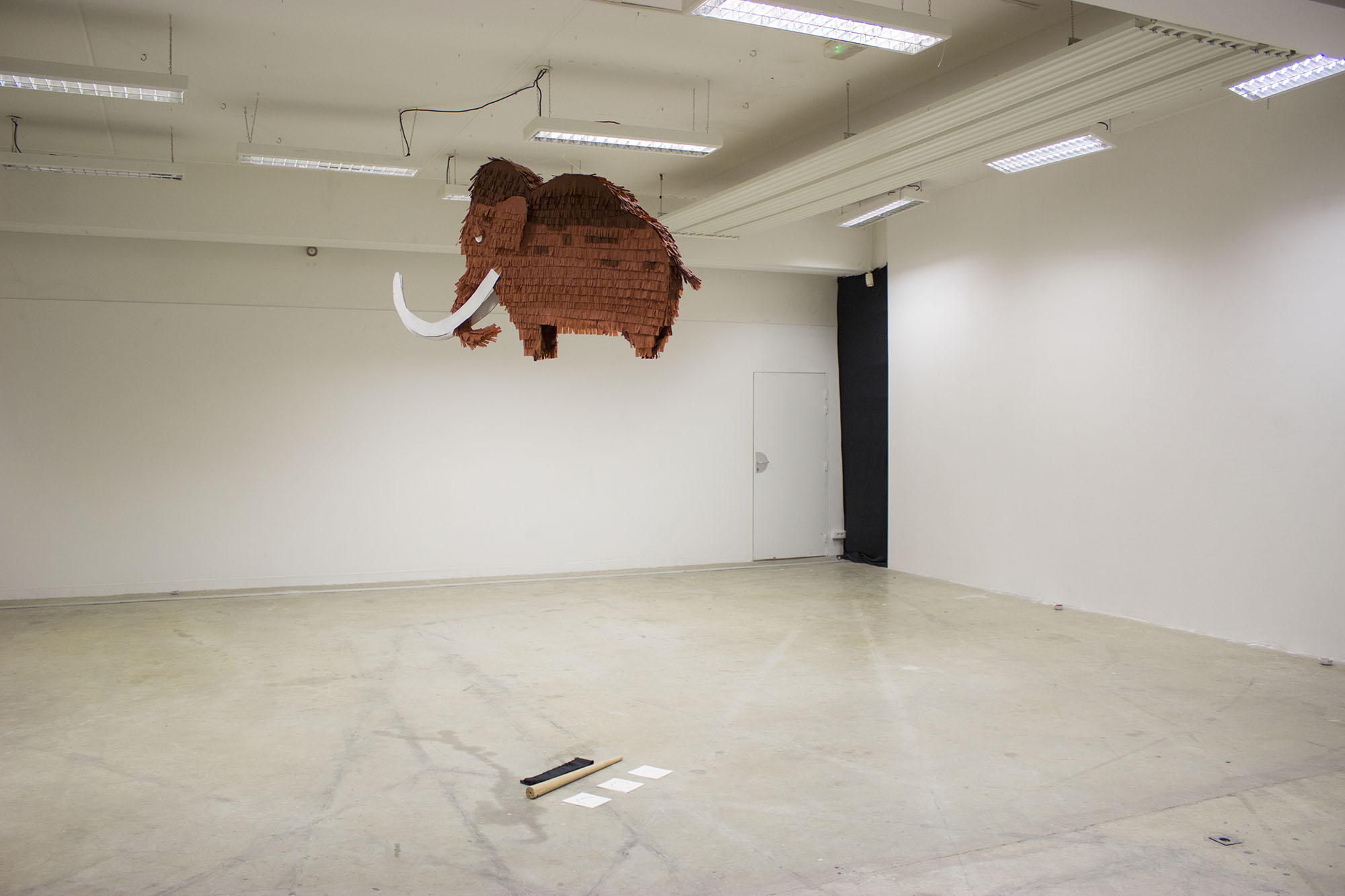 dans une salle vide, une piñata de mammouth es accroché au plafond.