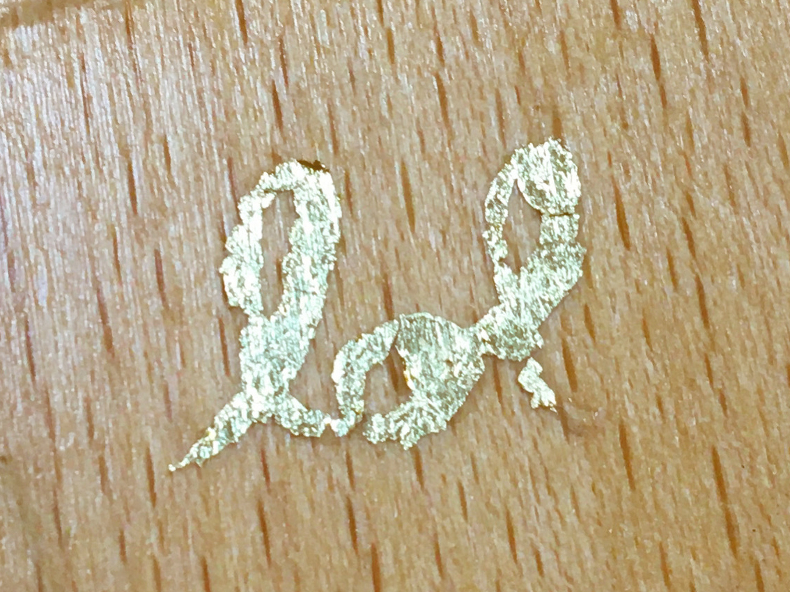 Sur une planche de bois on voit écrit LOL à la feuille d'or.
