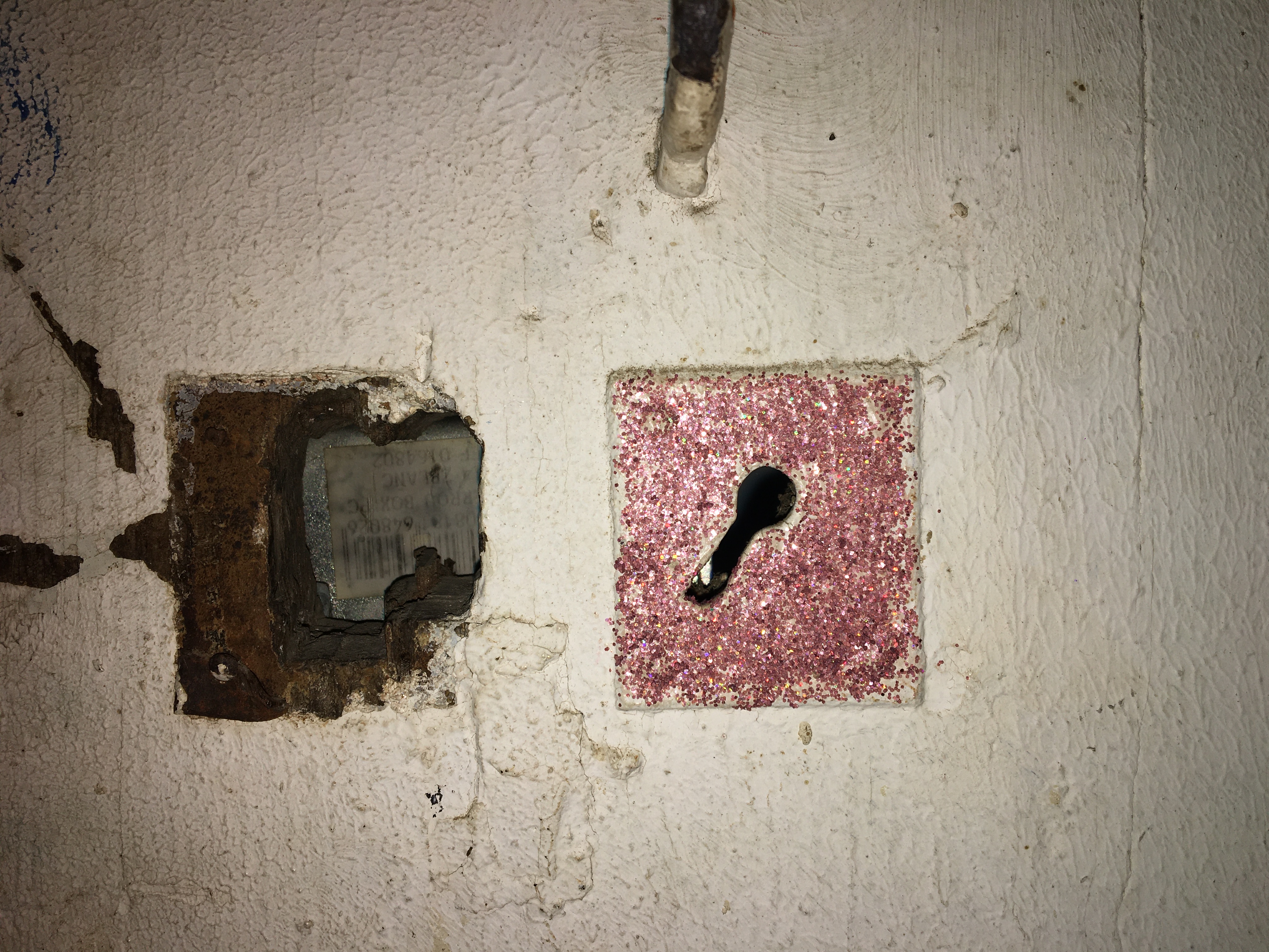 Une vieille serrure dans uen porte en bois a été entouré d'un carré de paillettes roses.