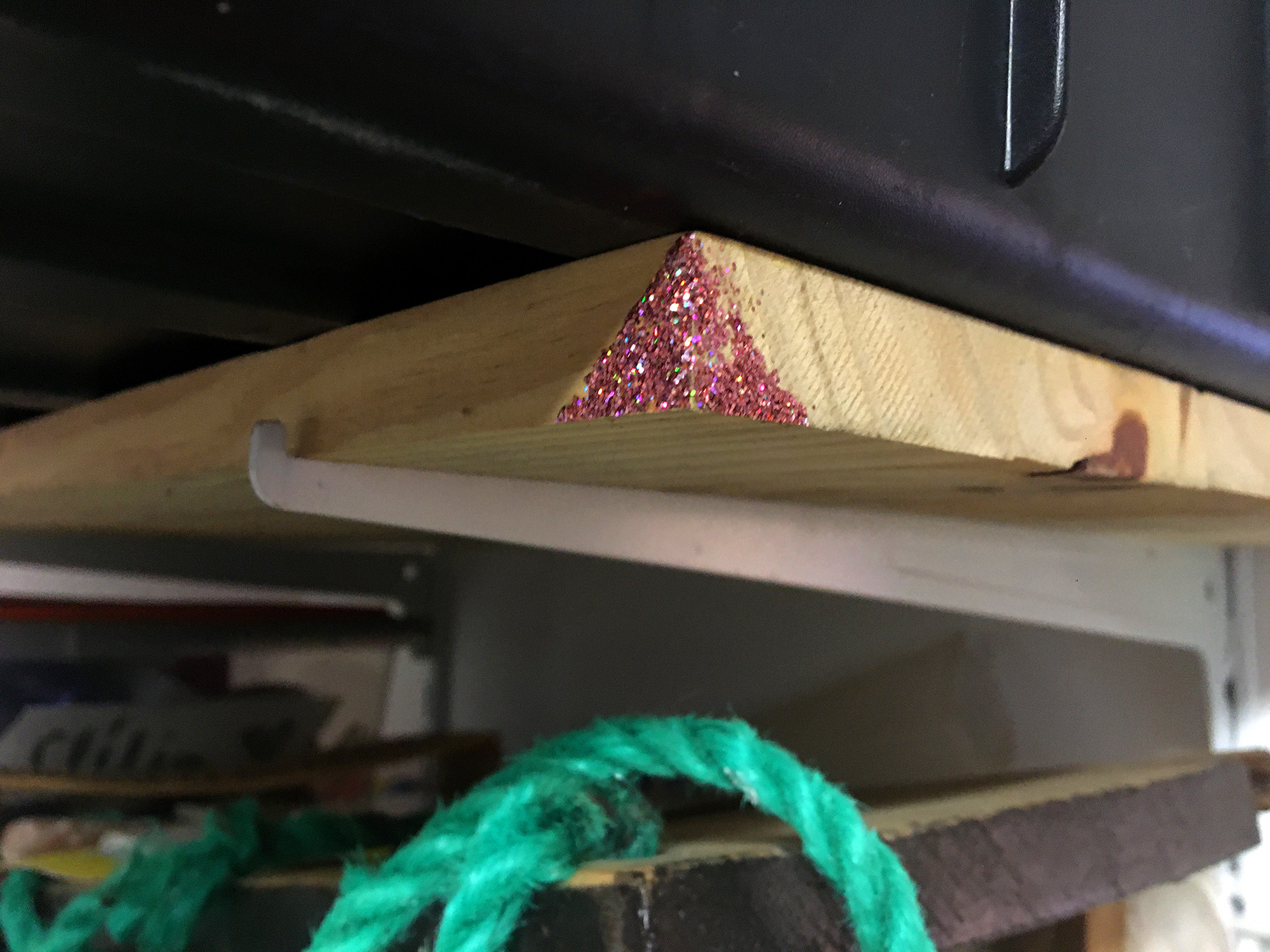 Gros plan sur un angle pailleté de l'étagère. On voit qu'une partie a déjà été abimée, certainement quelqu'un qui s'est cogné.
