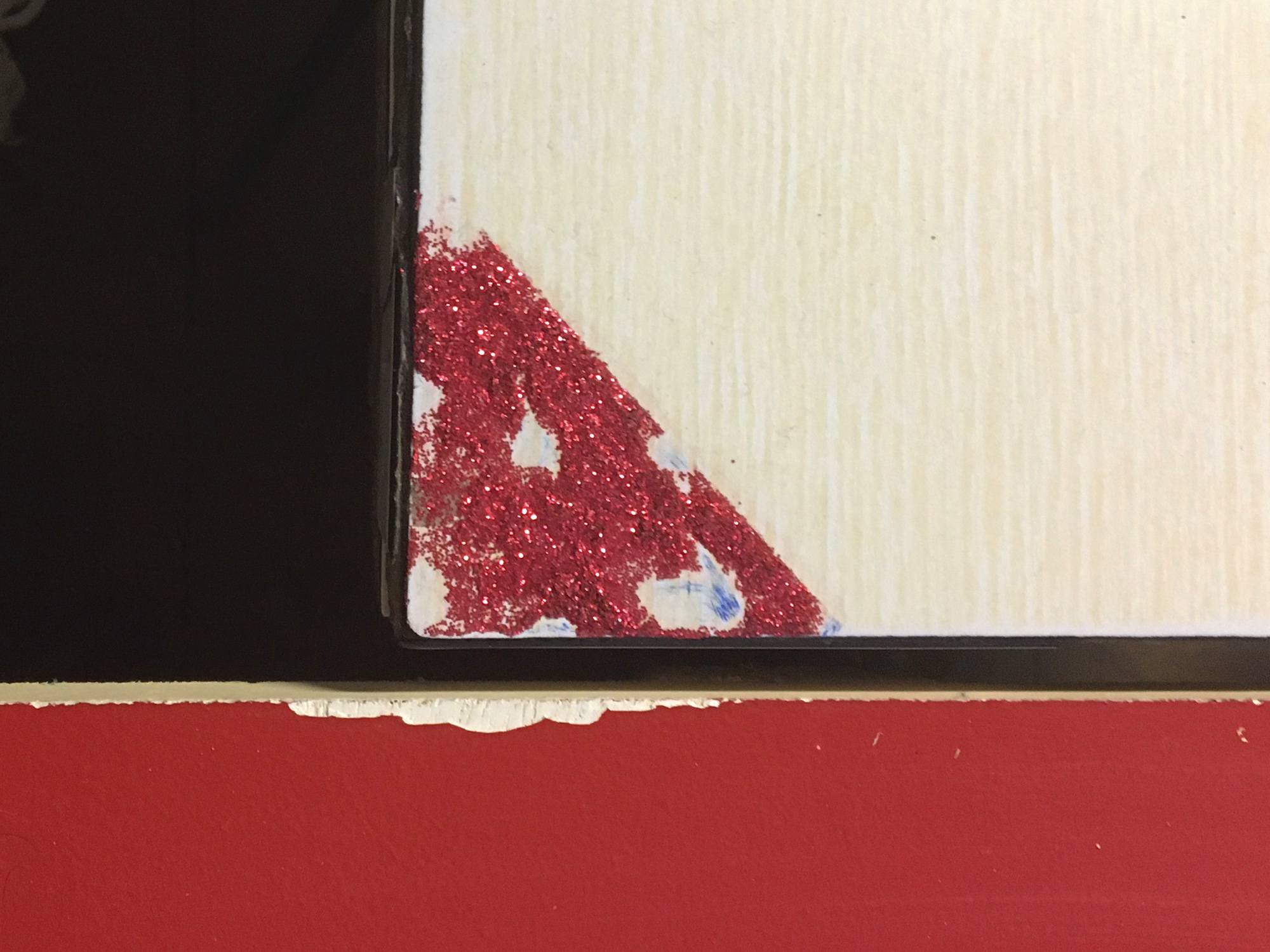 Gros plan sur le même angles de la table que précédemment, le triangle rouge de paillettes a été abimé, certainement à cause de friction 