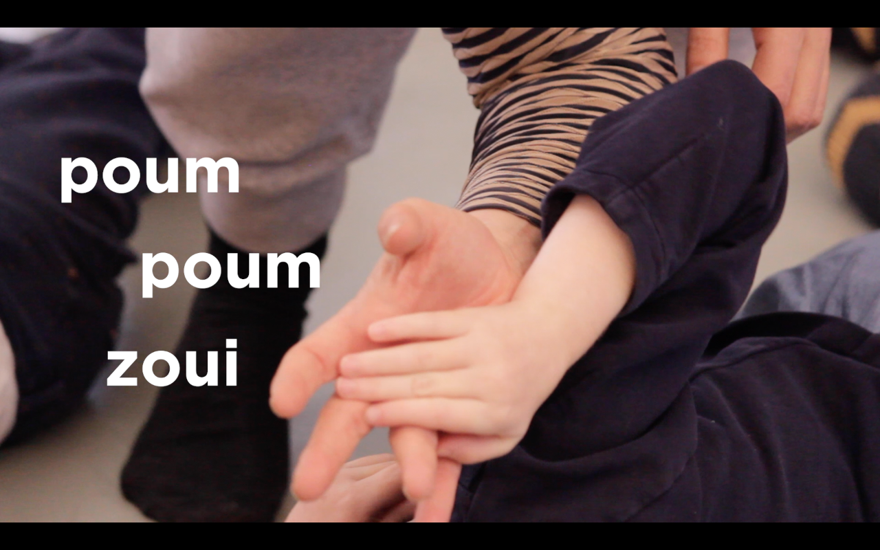 La main d'un enfant est poussée par celle d'un adulte. On voit le titre d film Poum poum zoui en lettres blanches