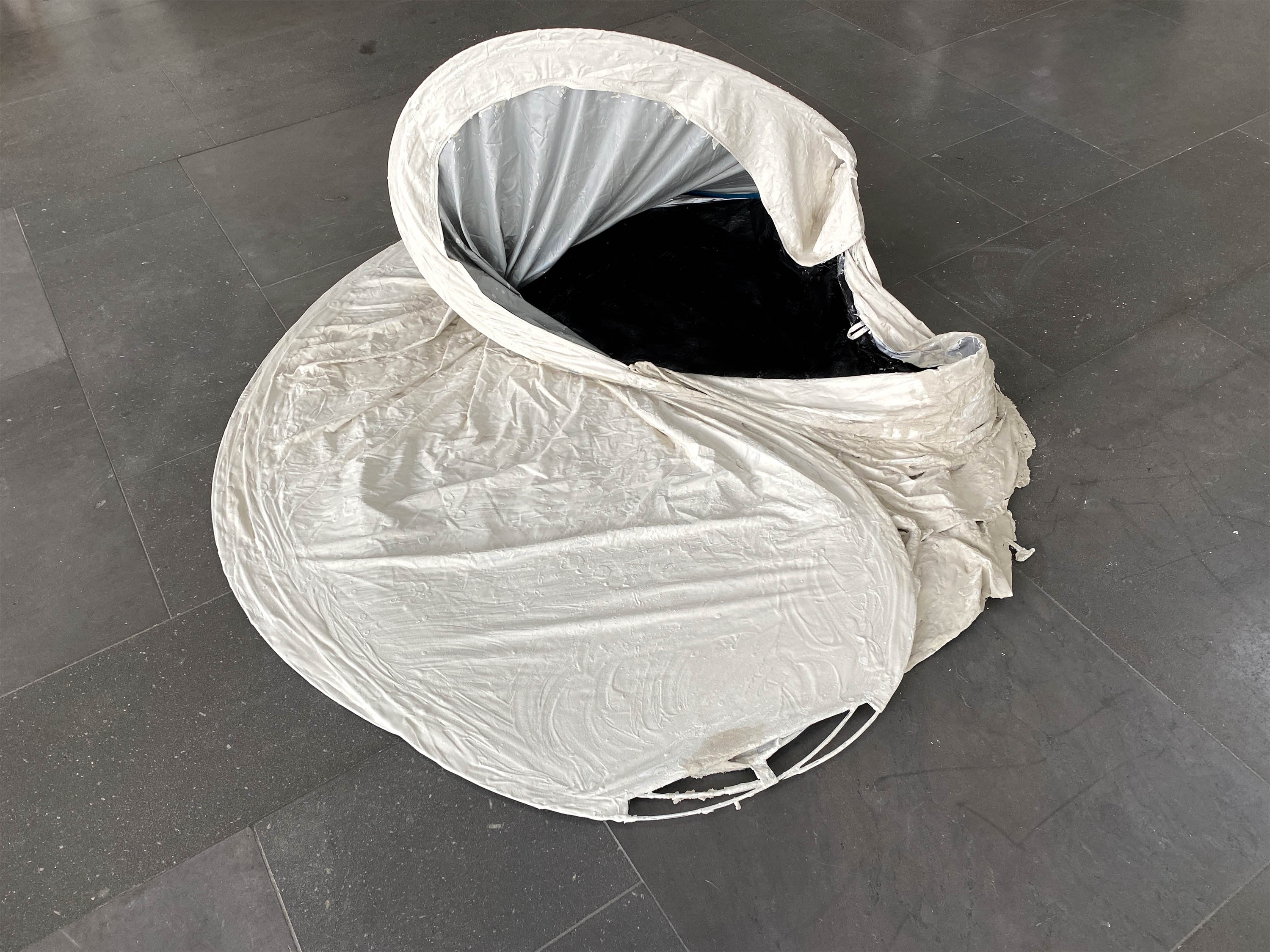 une tente pliable est à moitié repliée et recouverte de mortier sur la partie extérieure. vue de face