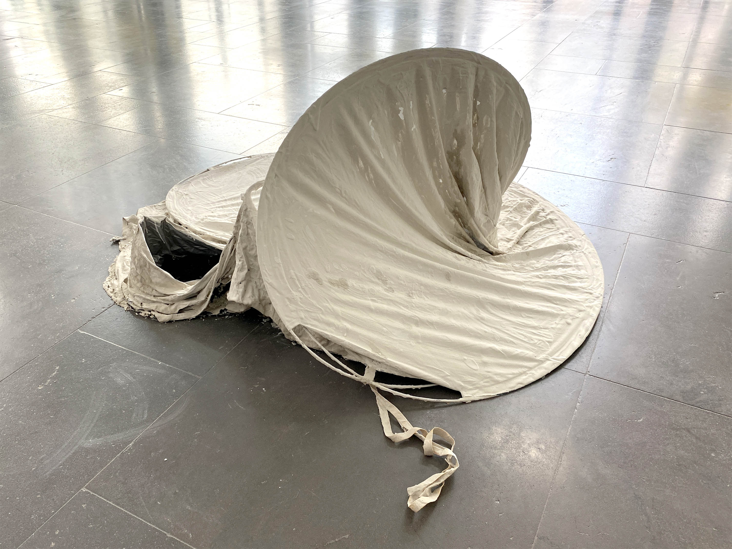 une tente pliable est à moitié repliée et recouverte de mortier sur la partie extérieure. vue de dos
